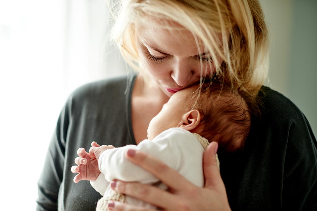 New mother holding and kissing her baby