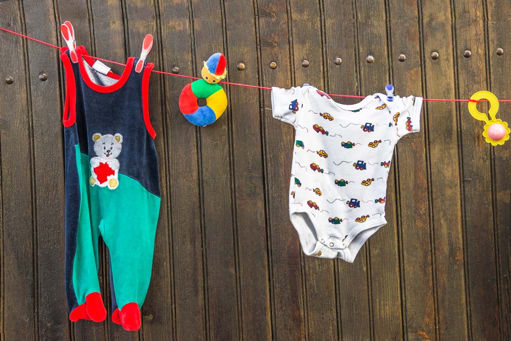 Baby clothes and toys on washing line symbolising preparation for life with a new baby